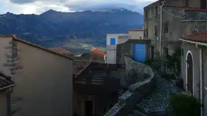 Pueblo de montaña con casas de piedra y tejados de teja, rodeado de picos nevados en la sierra