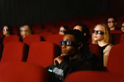 Familia viendo película animada en pantalla de cine en 3D, iluminados por la luz de la pantalla.