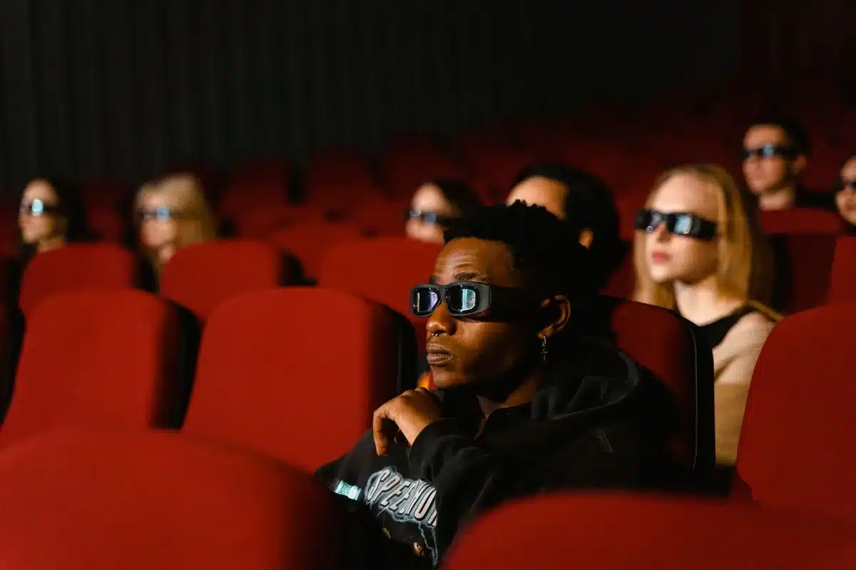 Familia viendo película animada en pantalla de cine en 3D, iluminados por la luz de la pantalla.