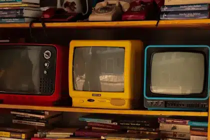 Gafas 3D de cartón rojo y azul sostenidas frente a un televisor antiguo en una sala oscura