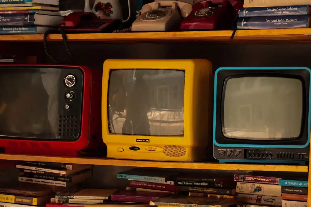 Gafas 3D de cartón rojo y azul sostenidas frente a un televisor antiguo en una sala oscura