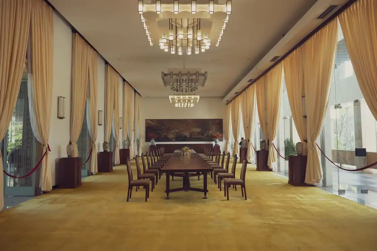 Sala de recepción formal en palacio con luz de tarde filtrándose por ventanas altas