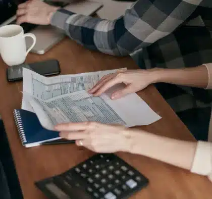 Manos sobre documentos de pensión y calculadora, comparando cifras de jubilación