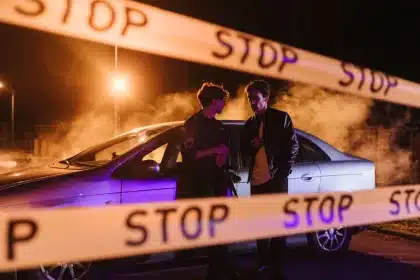 Escena nocturna de investigación policial con vehículos de emergencia y cinta de seguridad en una zona acordonada