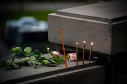 Velas y flores en memoria de víctimas de atentado, en plaza urbana al atardecer