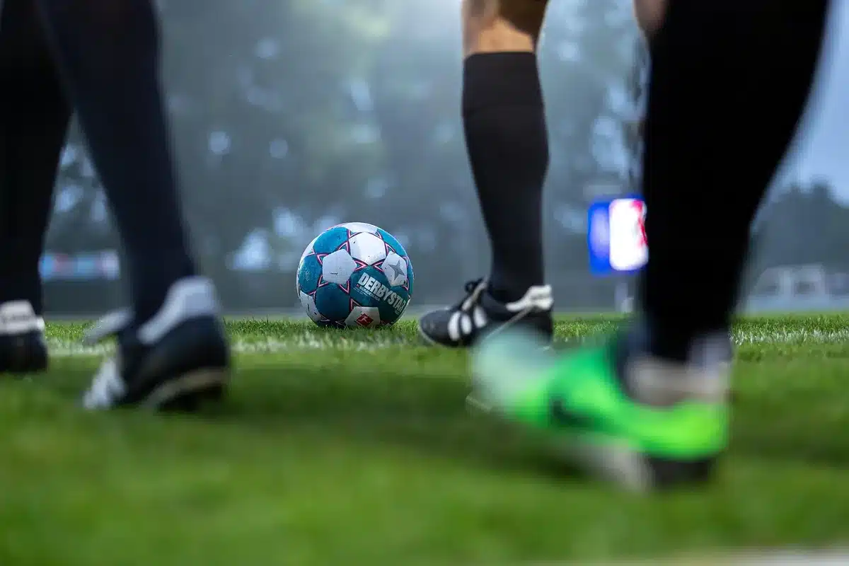 Empty victory celebration scene on a football pitch with anonymous silhouettes, a single unbranded ball on the grass, stadium lights in the background