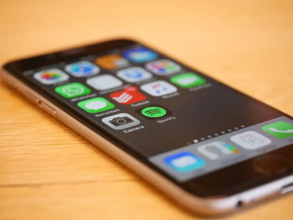 Anonymous hands holding an unbranded smartphone, screen showing a generic update progress bar, blurred background of a desk