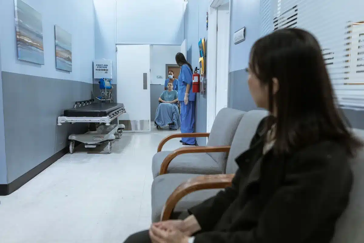 Interior corridor view of a bright, empty hospital ward with new signage pillars and seating, no people present