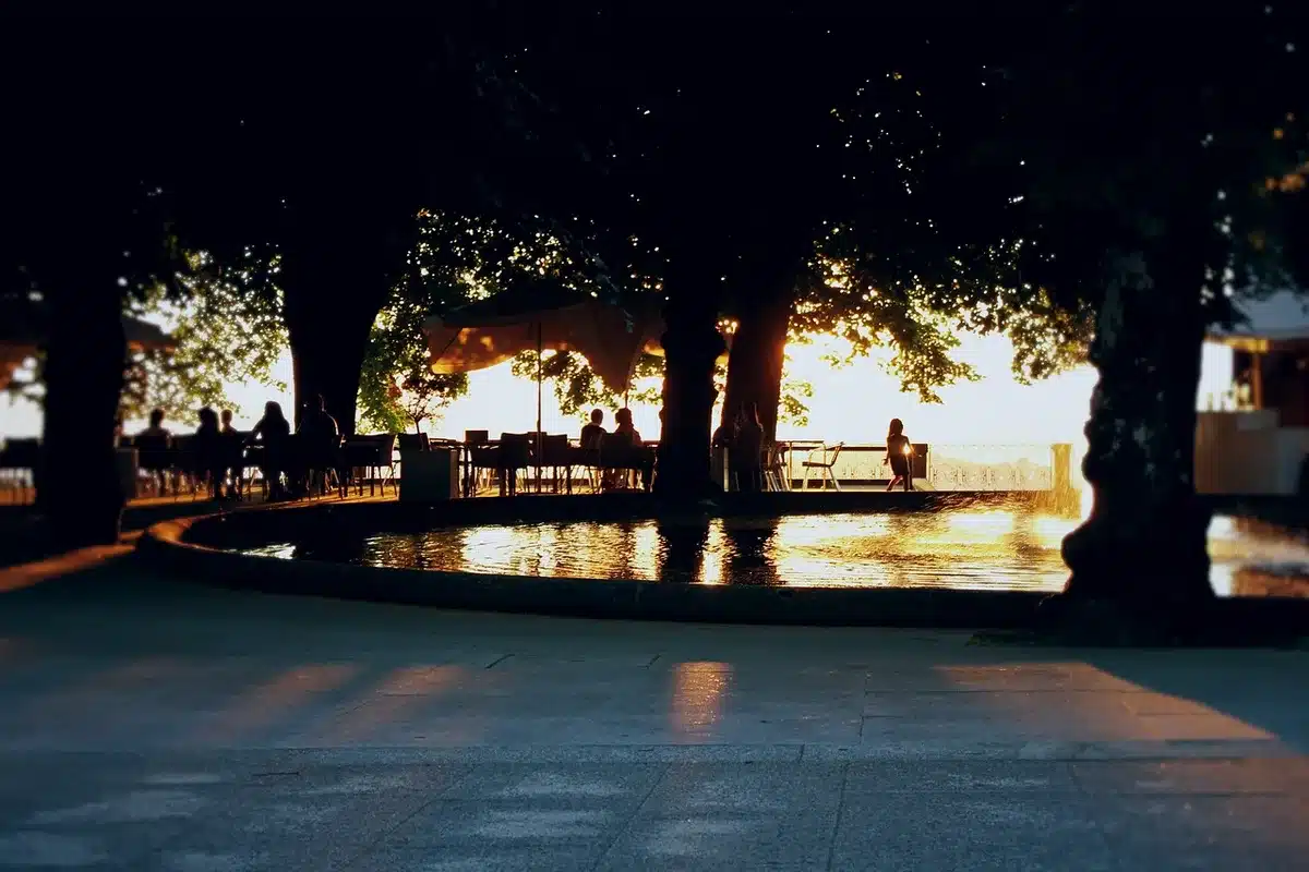 Empty street terrace with stacked chairs and a small unbranded cafe window at dusk, no people visible