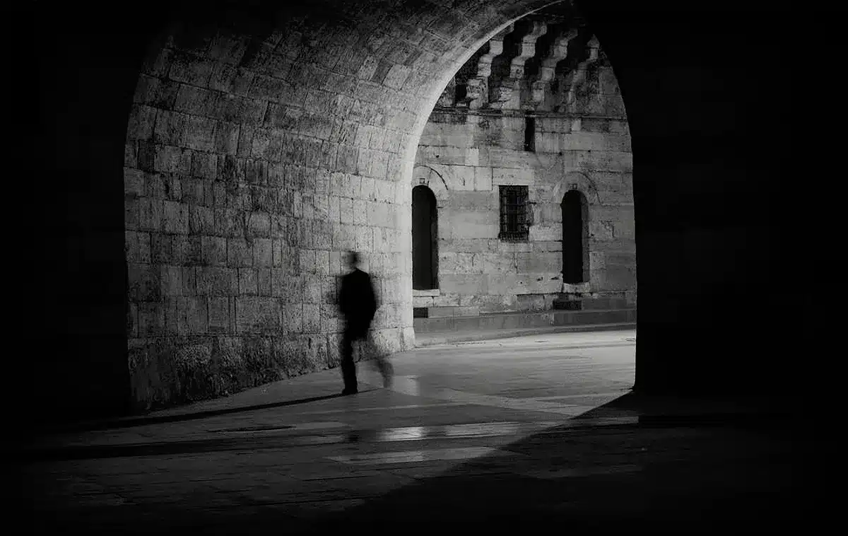 Interior view down a short vaulted brick corridor with soft modern lighting, no people, historical plaque visible on the wall