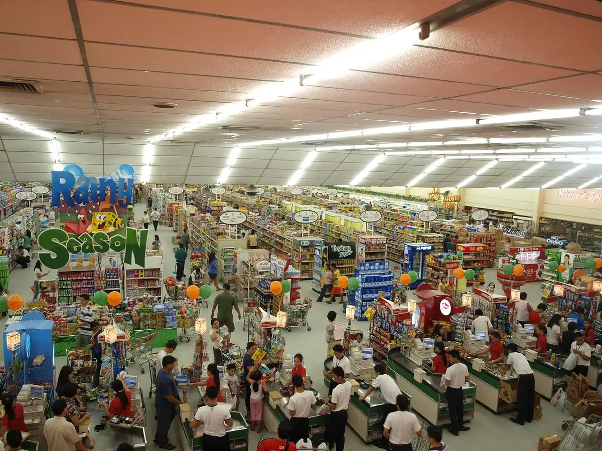 Interior view showing anonymous employees stocking shelves, wide aisles and product displays, no brand visible