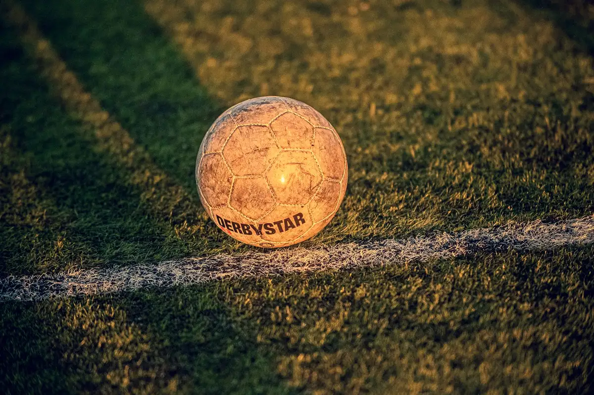 Close-up of a generic matchball on the turf near the penalty area with empty stands beyond