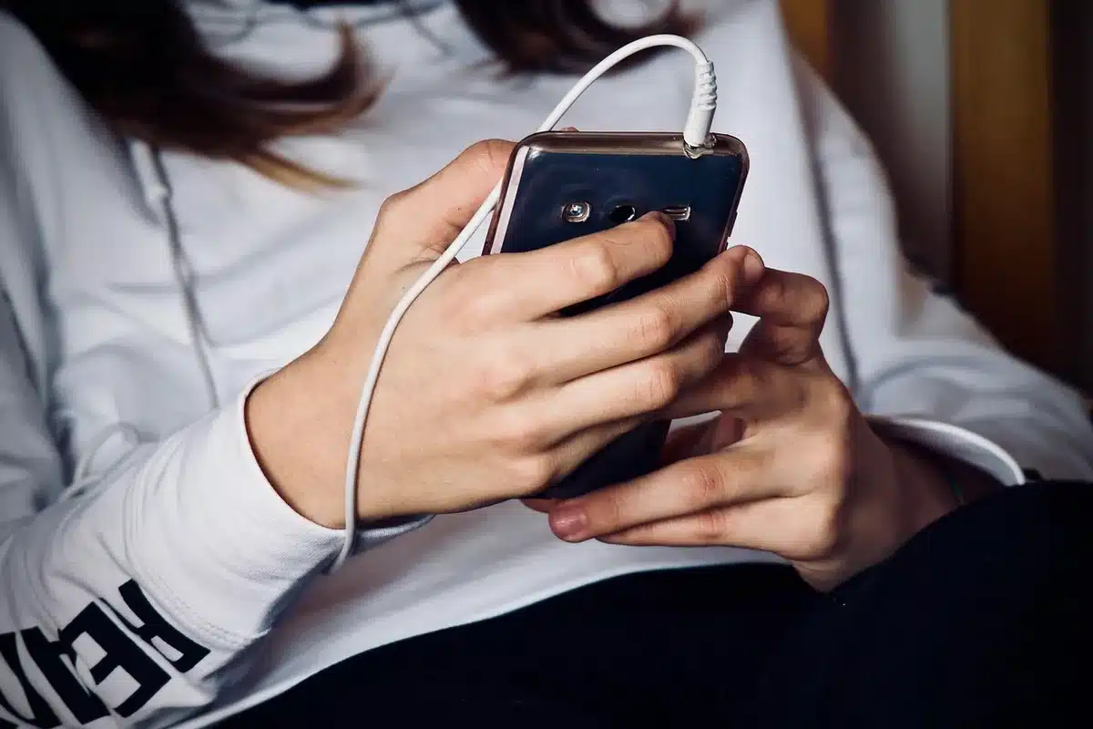 Close-up of anonymous hands unboxing a generic smartphone, a small update notification card visible but unreadable, blurred background
