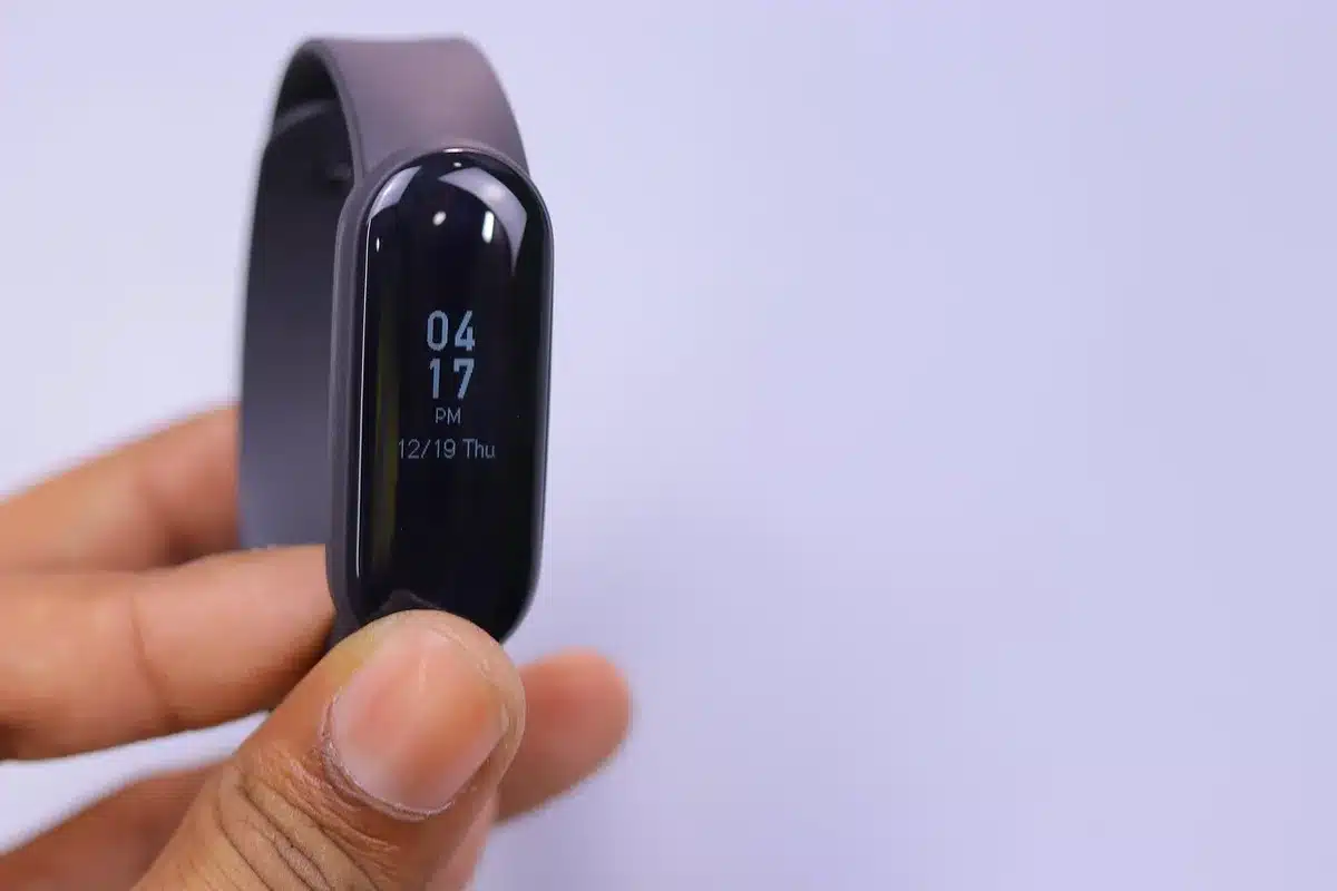 Anonymous close-up of a smartwatch screen showing generic fitness rings and icons, hand-held with blurred background, no logos visible