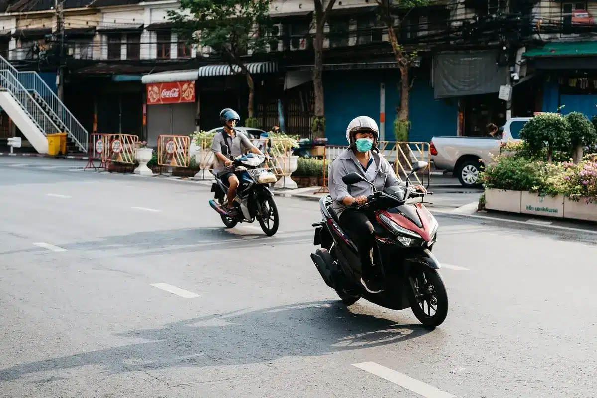 An anonymous close-up of an unbranded motorcycle helmet resting on a scuffed racetrack asphalt; blurred tire marks and a distant empty pit lane create tension