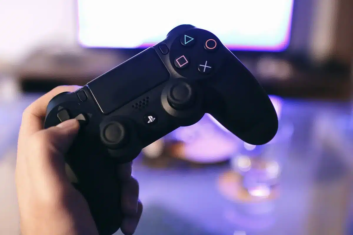 Anonymous hands holding an unbranded wireless game controller above a smartphone screen showing a generic cursor