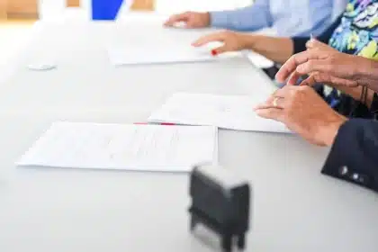 Manos anónimas desplazando carpetas judiciales sobre una mesa en una oficina institucional