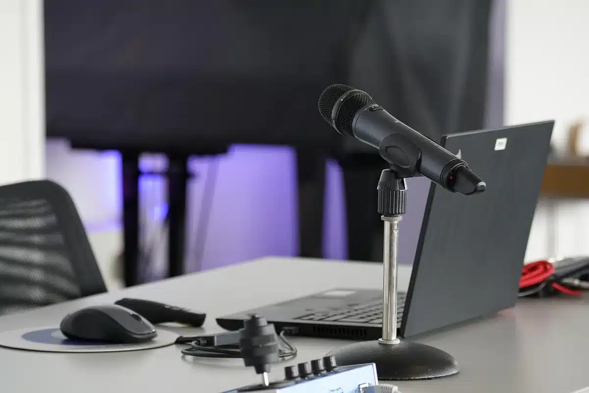 Empty stage with a single microphone under a spotlight, dust motes visible, no logos or text