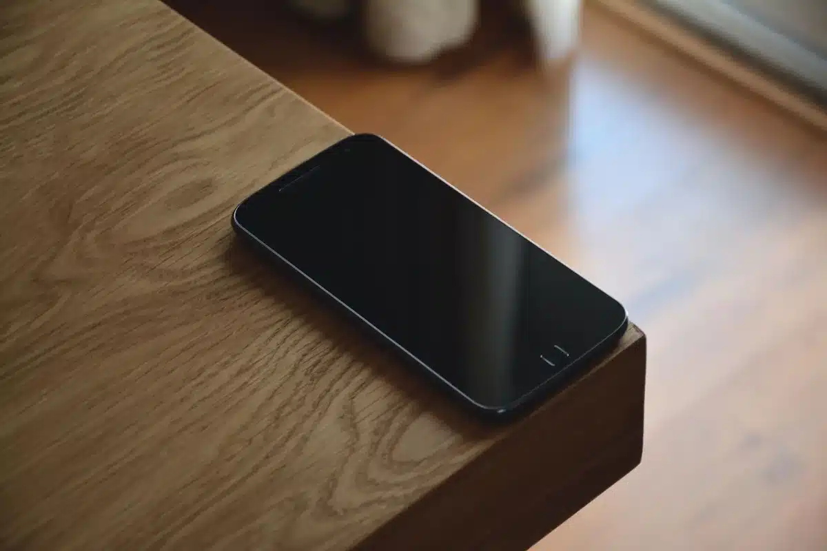 A single unbranded smartphone on a neutral wooden table, screen dim with a pulsing notification dot; no logos or text