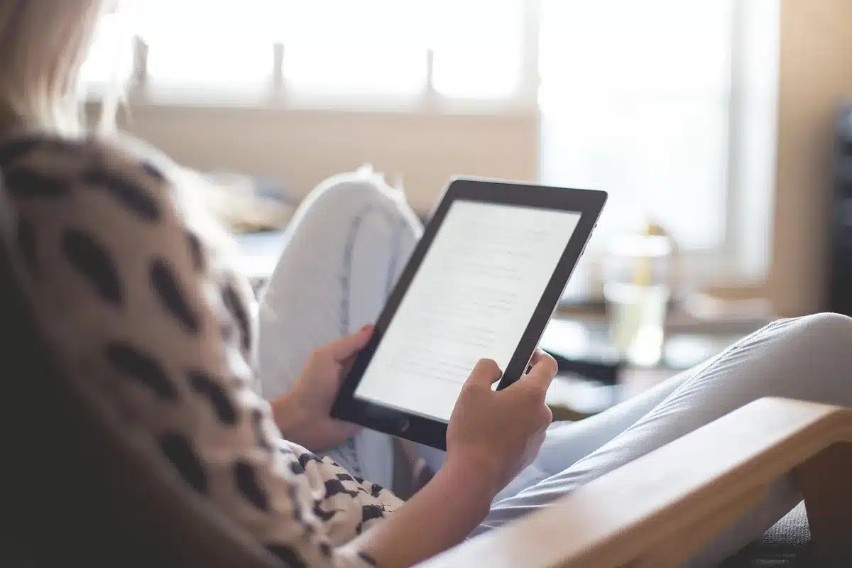 A close-up of anonymous hands holding a generic tablet displaying abstract app icons blurred out, suggesting withheld features; no identifiable people or logos