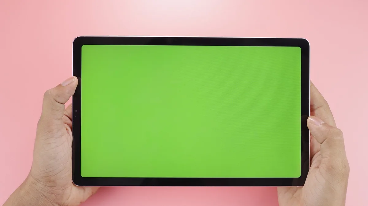 A minimalist tablet display on a neutral pedestal with no logos, thin bezels and a softly glowing screen suggesting OLED; empty dark studio background