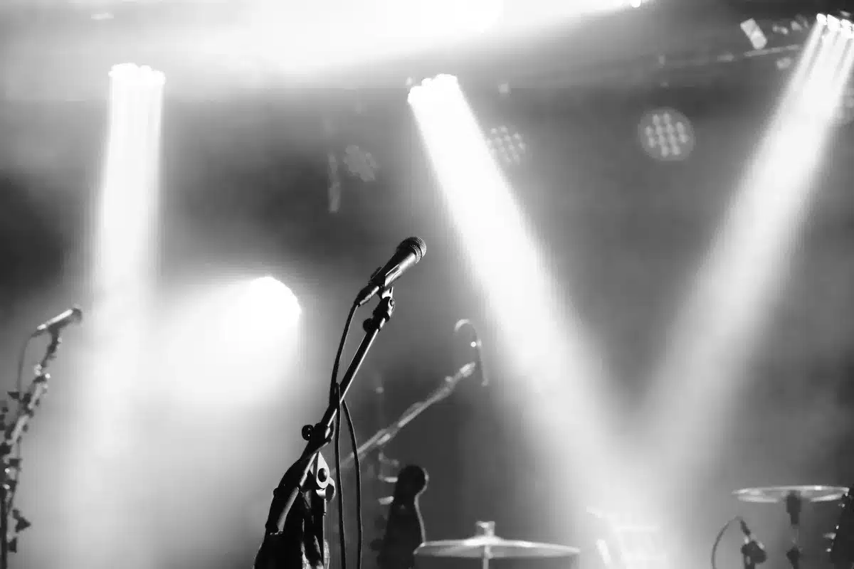 Empty stage with a single microphone under a spotlight, no logos or text, dust motes visible