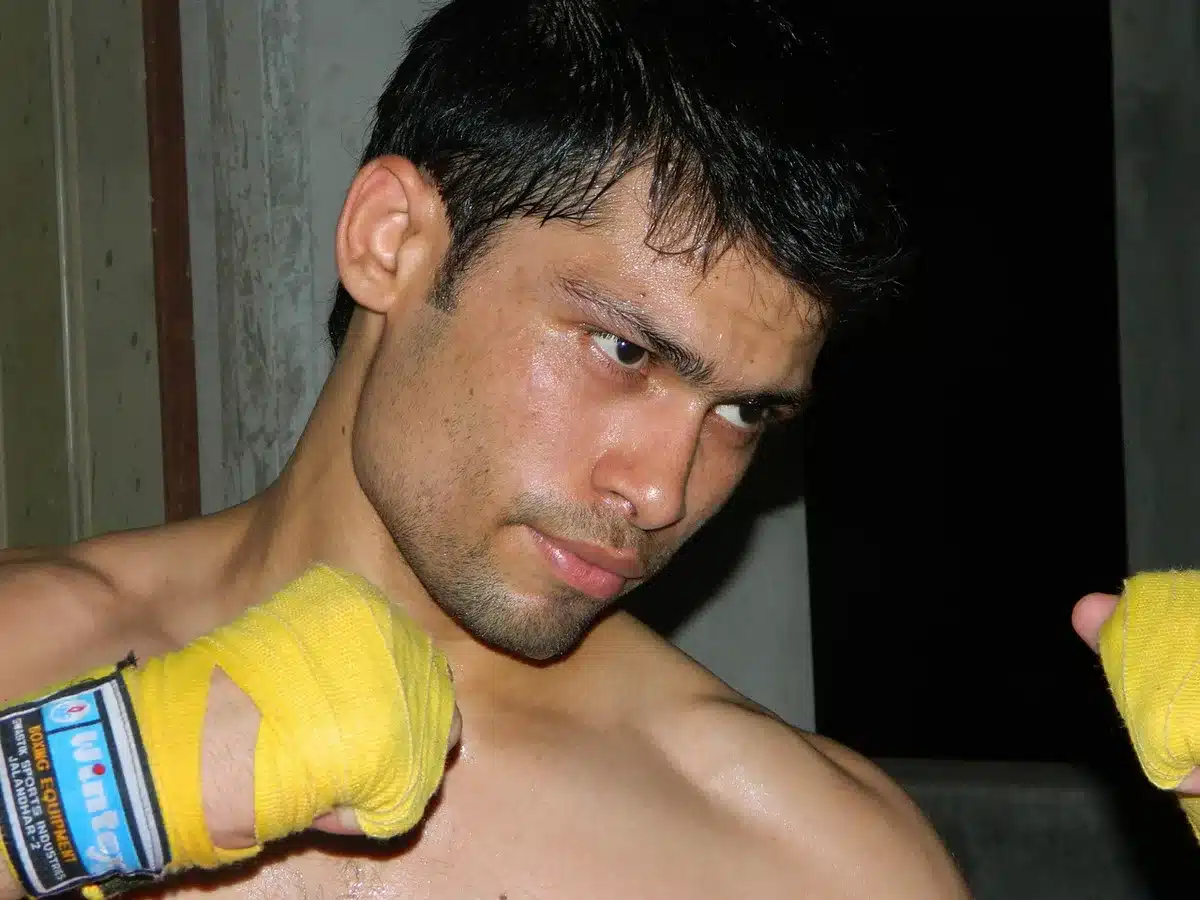 Close-up of an anonymous pair of gloved hands resting on the canvas edge of an octagon, arena lights blurred in background, no faces or logos