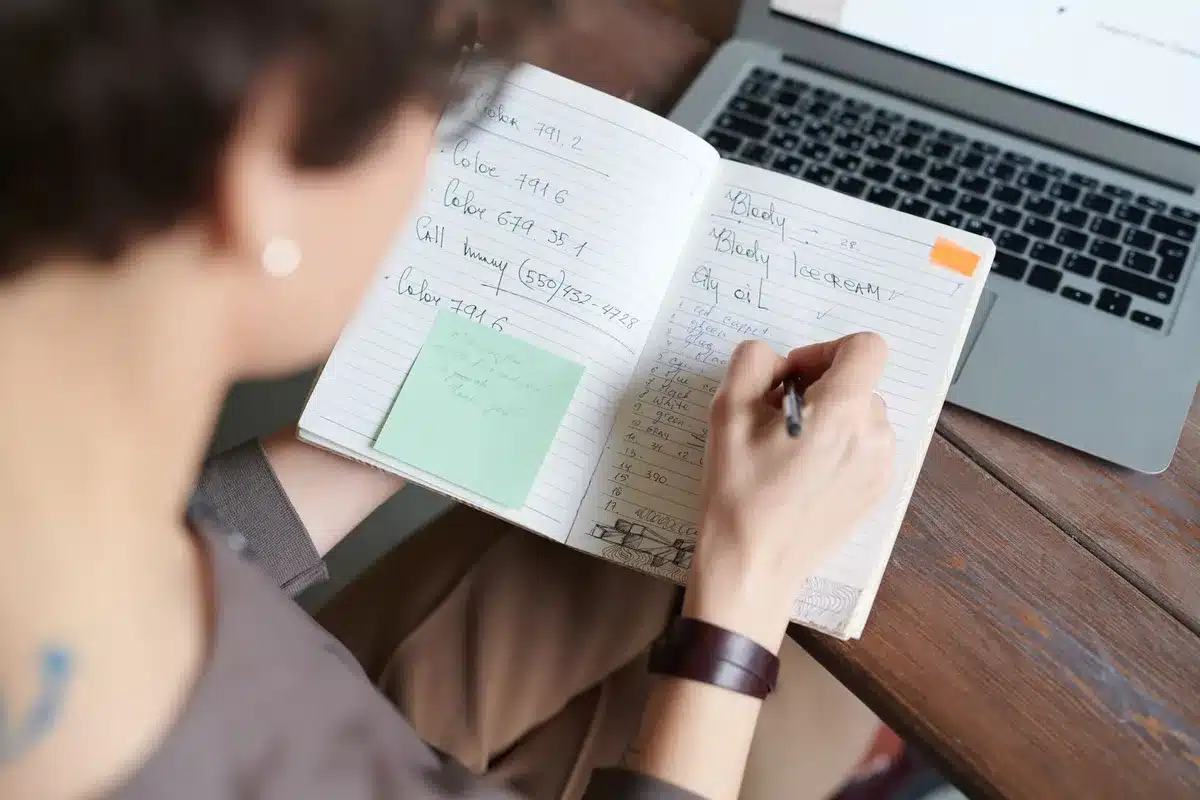 A close-up of a closed personal notebook with handwritten notes and a fountain pen on a desk, an anonymous research scene suggesting biography work