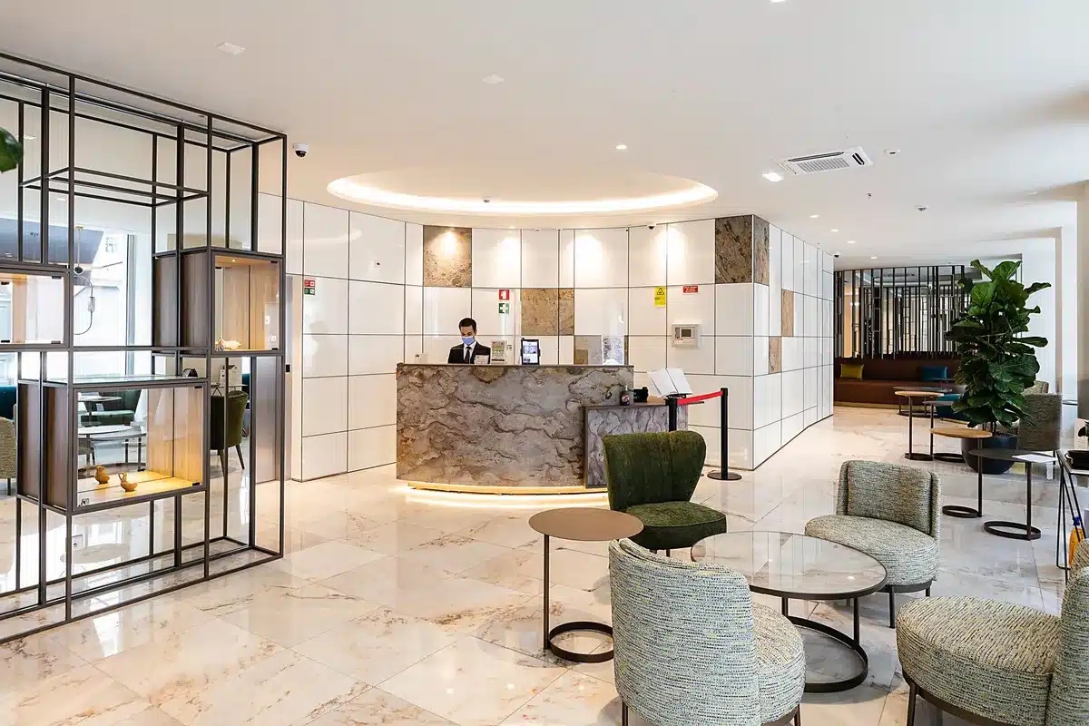 Empty elegant hotel salon with a single long table and several chairs arranged for a formal reception, soft natural light through tall windows, no people