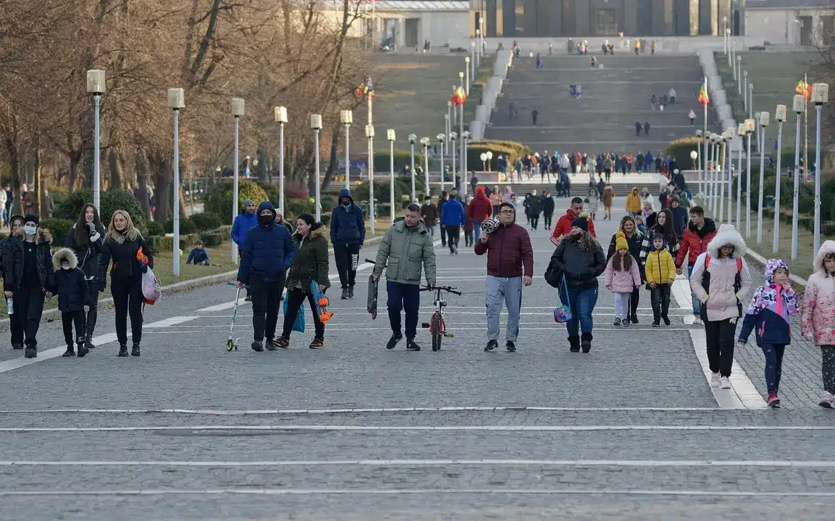 Group of anonymous people in motion blur outside a grand congress hall, umbrellas and autumn coats, press photographers in distance, overcast sky