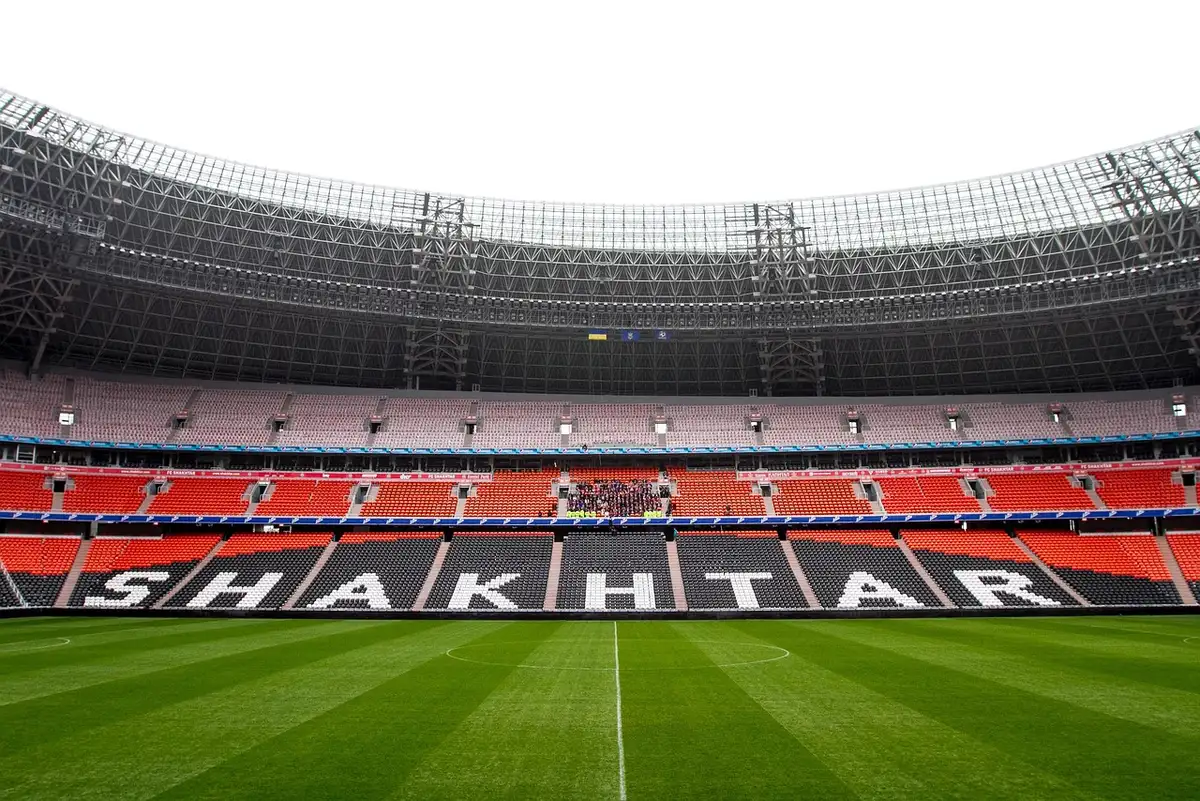 Close shot of empty stadium steps with a discarded paper cup beside a seat, floodlights on