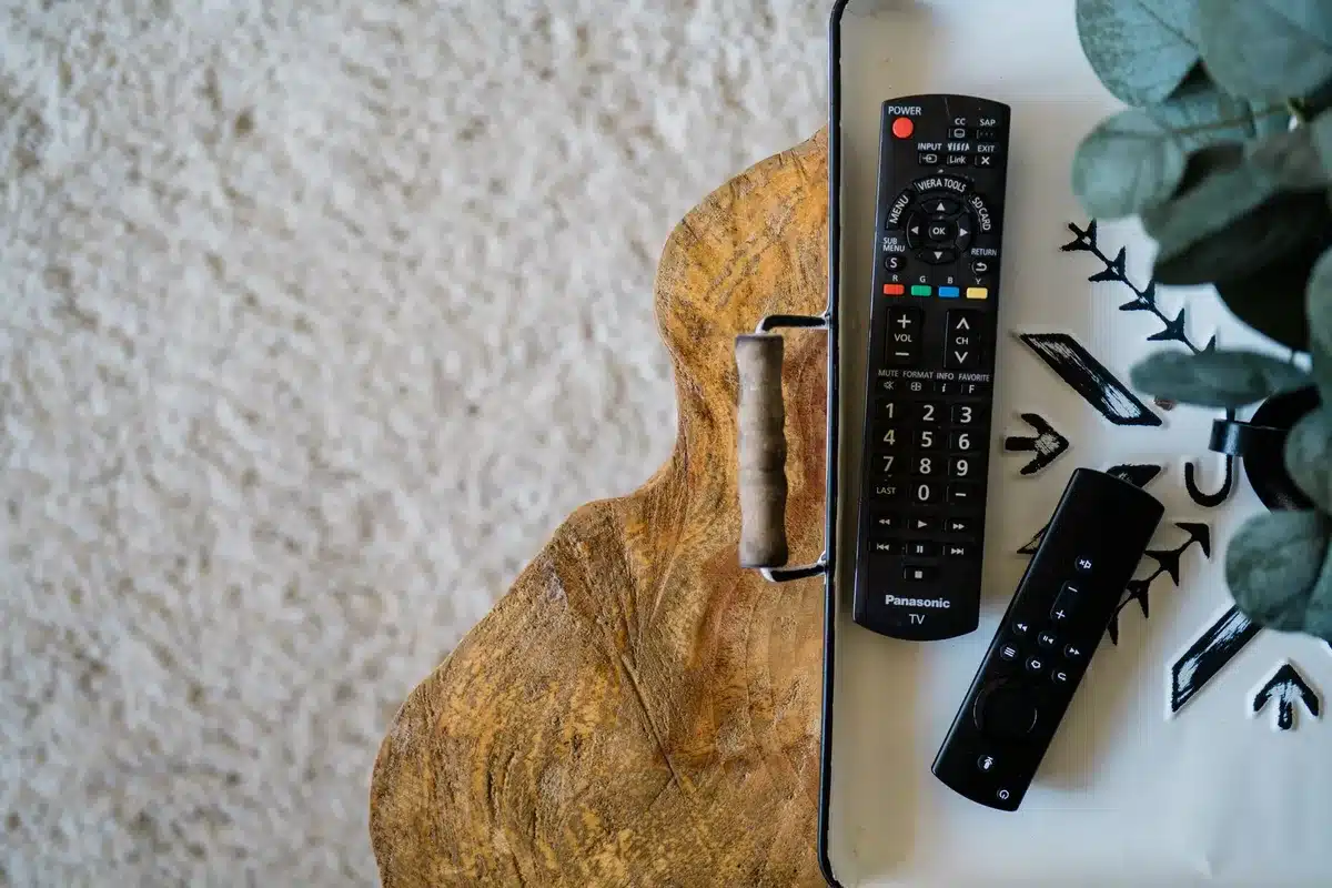 Close-up of an unbranded TV remote and a streaming guide page showing channel numbers without logos