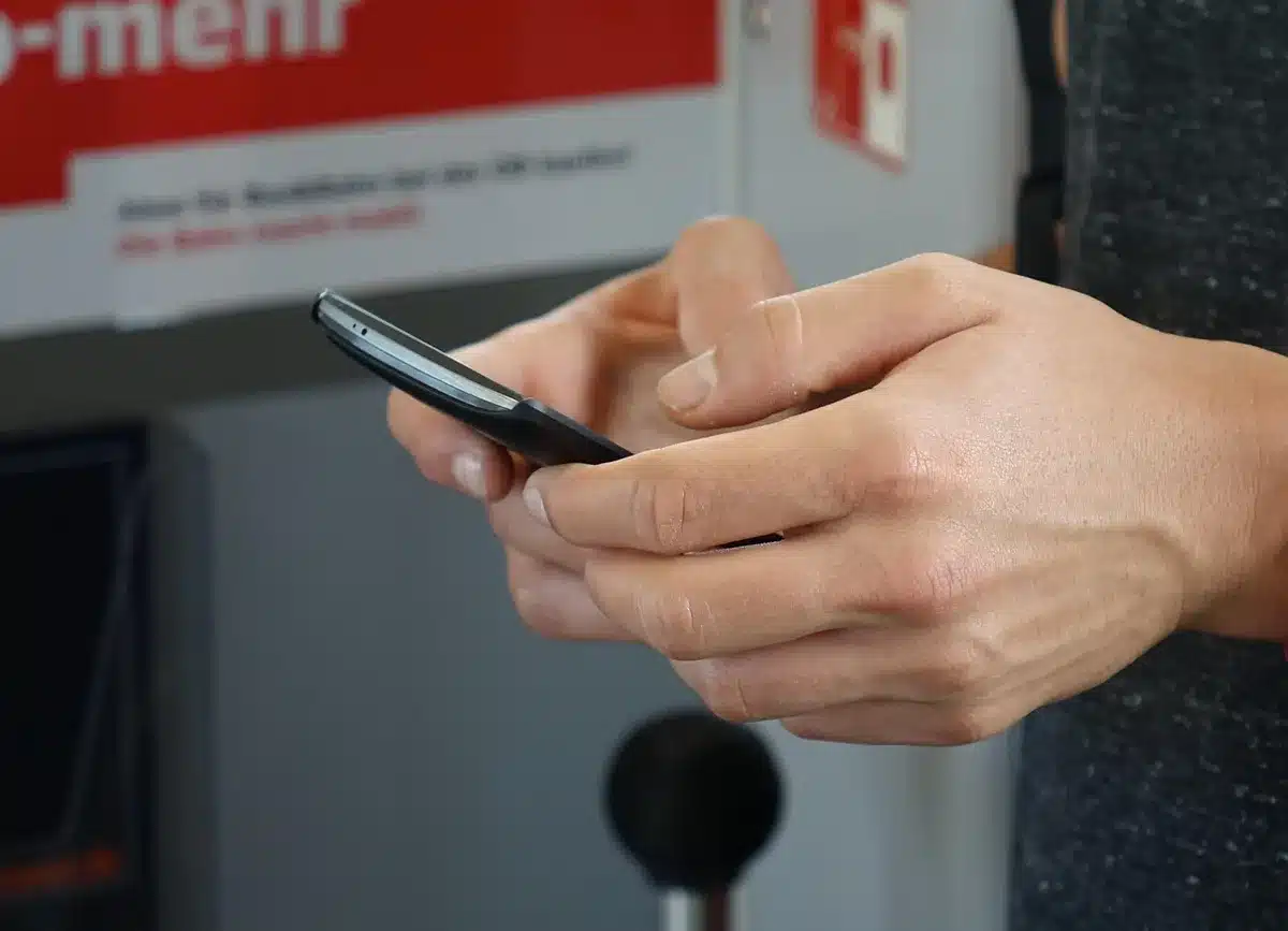 close-up of hands holding a smartphone showing an anonymous verification code input screen, fingers typing, no brand visible